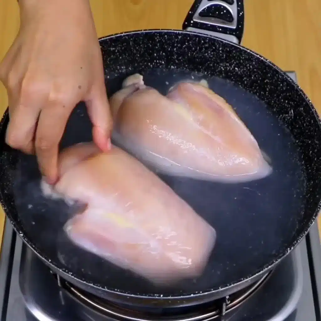 Plato de pollo hervido con verduras frescas y especias.